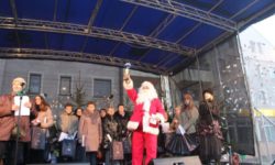 Zdjęcie przedstawia św. Mikołaja na scenie z nagrodą w ręce
