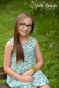 Zdjęcie przedstawia dziewczynkę uśmiechniętą w okularach
