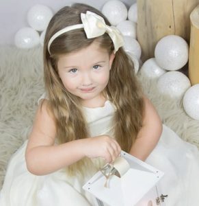 Zdjęcie przedstawia dziewczynkę w białej sukience