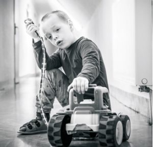 Zdjęcie przedstawia chłopca z zabawkowym samochodem