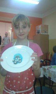 Zdjęcie przedstawia dziewczynę prezentującą ciastko na talerzu