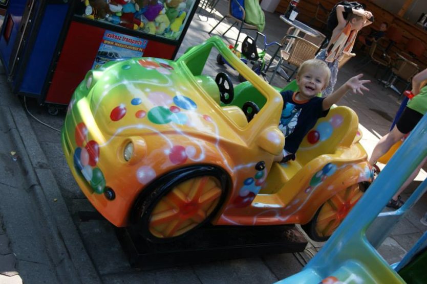 Zdjęcia przedstawia chłopczyka siedzącego na samochodzie