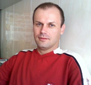 Zdjęcie przedstawia mężczyznę w czerwonej bluzce