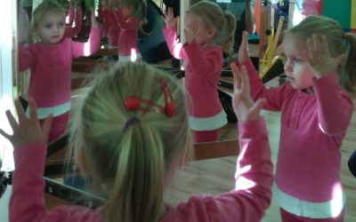Zdjęcie przedstawia dziewczynkę ubraną na różowo przed lustrem
