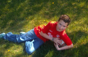 Zdjęcie przedstawia chłopaka leżącego na trawie