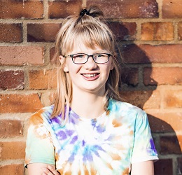 Zdjęcie przedstawia dziewczynkę uśmiechniętą w okularach