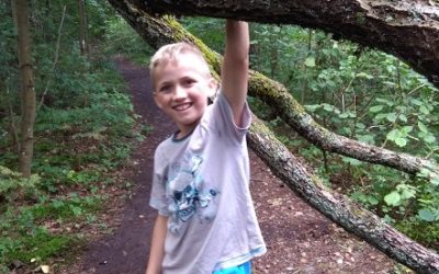 Zdjęcie przedstawia chłopaka opierającego się o gałąź drzewa