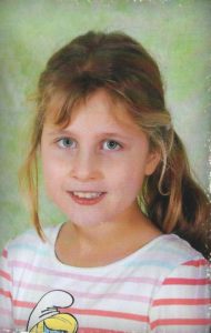 Zdjęcie przedstawia dziewczynkę w bluzce z kolorowymi paskami