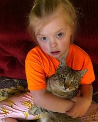 Zdjęcie przedstawia dziewczynkę z kotkiem