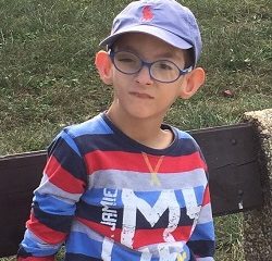 Zdjęcie przedstawia chłopca w okularach w czapce z daszkiem