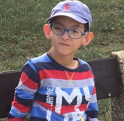 Zdjęcie przedstawia chłopca w okularach w czapce z daszkiem