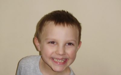 Zdjęcie przedstawia chłopczyka w szarej bluzce