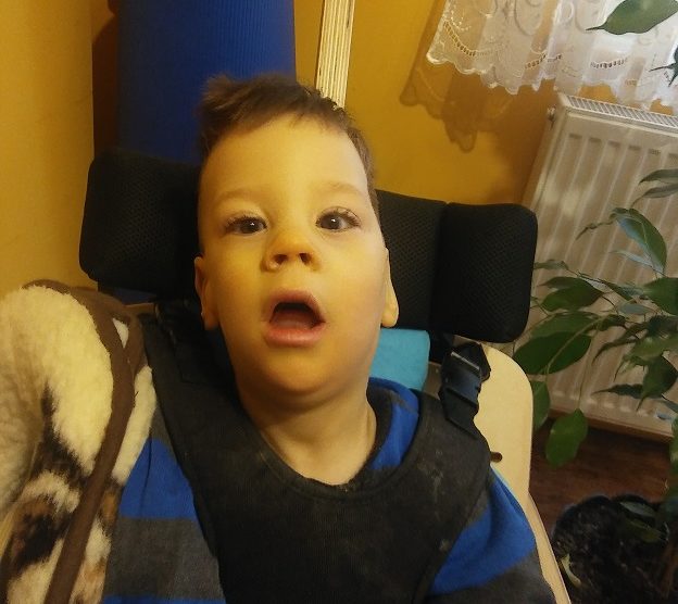 Zdjęcie przedstawia chłopczyka na wózku w bluzce w paski