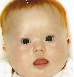 Zdjęcie przedstawia maleńkiego chłopczyka w rudych włosach
