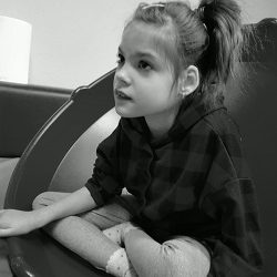 Zdjęcie przedstawia dziewczynkę siedzącą