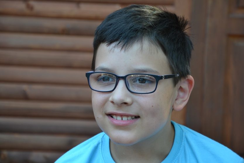 Zdjęcie przedstawia chłopczyka w niebieskiej bluzce w okularach