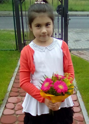 Zdjęcie przedstawia dziewczynkę uśmiechniętą z kwiatami