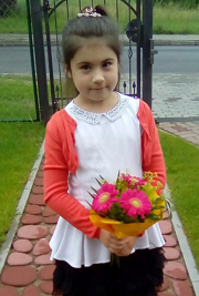 Zdjęcie przedstawia dziewczynkę uśmiechniętą z kwiatami