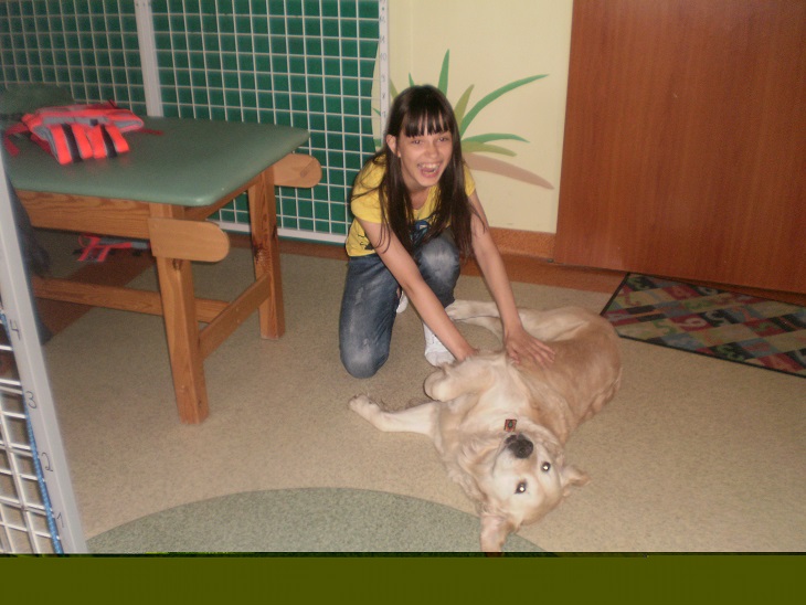 Zdjęcie przedstawia dziewczynkę bawiącą się z psem