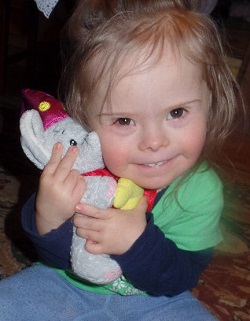 Zdjęcie przedstawia dziewczynkę uśmiechniętą z pluszakiem