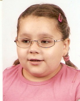 Zdjęcie przedstawia dziewczynkę w dwóch warkoczach różowej bluzce