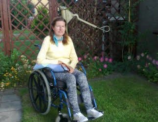 Zdjęcie przedstawia kobietę na wózku w ogrodzie
