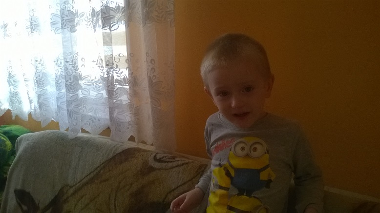 Zdjęcie przedstawia chłopczyka w szarej bluzce w minionki