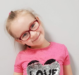 Zdjęcie przedstawia dziewczynkę w okularach