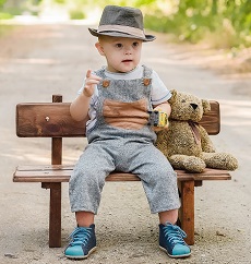 Zdjęcie przedstawia chłopca uśmiechniętego siedzącego na ławce
