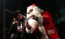 Zdjęcie przedstawia mężczyznę przebranego za Św. Mikołaja przy mikrofonie
