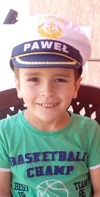 Zdjęcie przedstawia chłopca uśmiechniętego w czapce kapitana