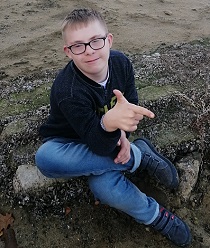 Zdjęcie przedstawia chłopca siedzącego na kamieniu