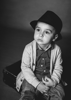 Zdjęcie przedstawia chłopca uśmiechniętego w kapeluszu