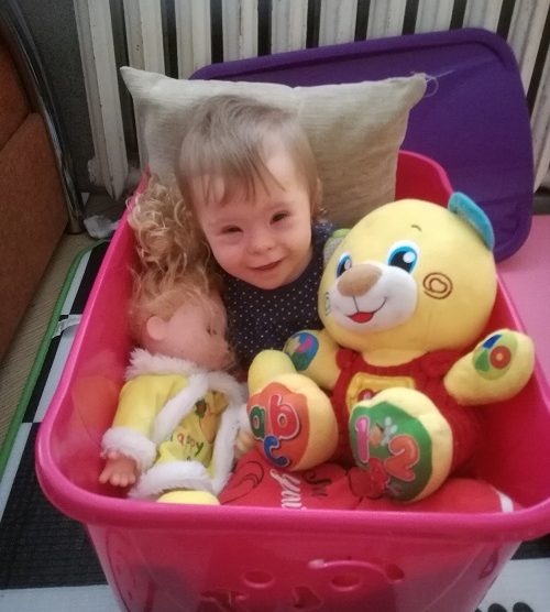 Zdjęcie przedstawia dziewczynkę uśmiechniętą z zabawkami