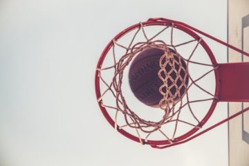 Zdjęcie przedstawia kosz do koszykówki z wpadającą do niego piłką