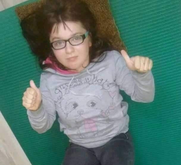 Zdjęcie przedstawia dziewczynkę uśmiechniętą w okularach leżącą