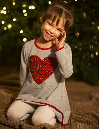 Zdjęcie przedstawia dziewczynkę w sukience szarej z czerwonym sercem