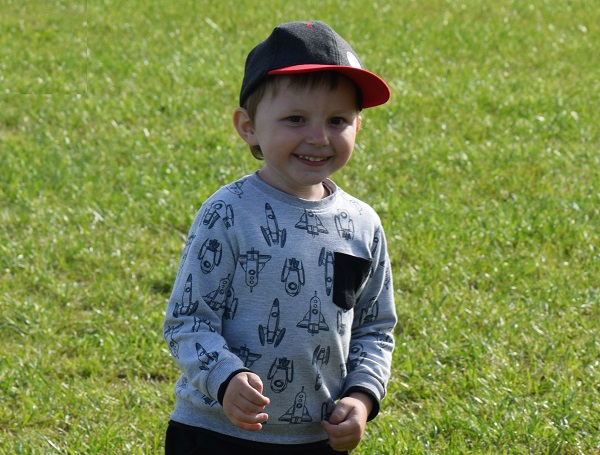 Zdjęcie przedstawia chłopca uśmiechniętego w czapce z daszkiem