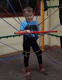Zdjęcie przedstawia chłopca uśmiechniętego ćwiczącego
