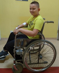 Zdjęcie przedstawia chłopca na wózku