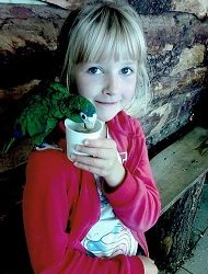 Zdjęcie przedstawia dziewczynkę uśmiechniętą z papugą