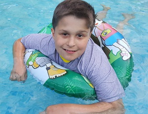 Zdjęcie przedstawia chłopca pływającego w kole na basenie