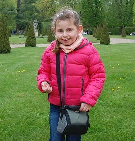 Zdjęcie przedstawia dziewczynkę uśmiechniętą z torebką