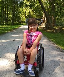 Zdjęcie przedstawia dziewczynkę na wózku