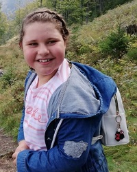 Zdjęcie przedstawia dziewczynkę z plecaczkiem na plecach