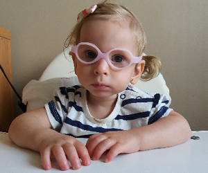 Zdjęcie przedstawia dziewczynkę w różowych okularach