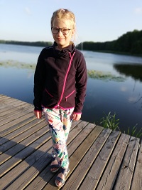 Zdjęcie przedstawia dziewczynkę w okularach na moście