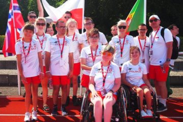 Zdjęcie przedstawia grupę sportowców oraz trenerów w Biało-Czerwonych strojach