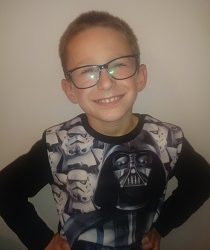 Zdjęcie przedstawia chłopca uśmiechniętego w okularach