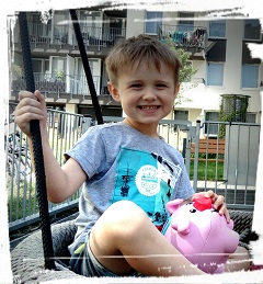 Zdjęcie przedstawia chłopca uśmiechniętego na huśtawce
